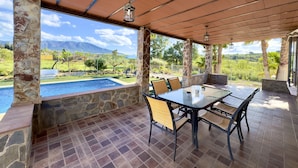 An outdoor patio with a pool, stone walls, and a table with chairs. - Finca Macías (Cártama)