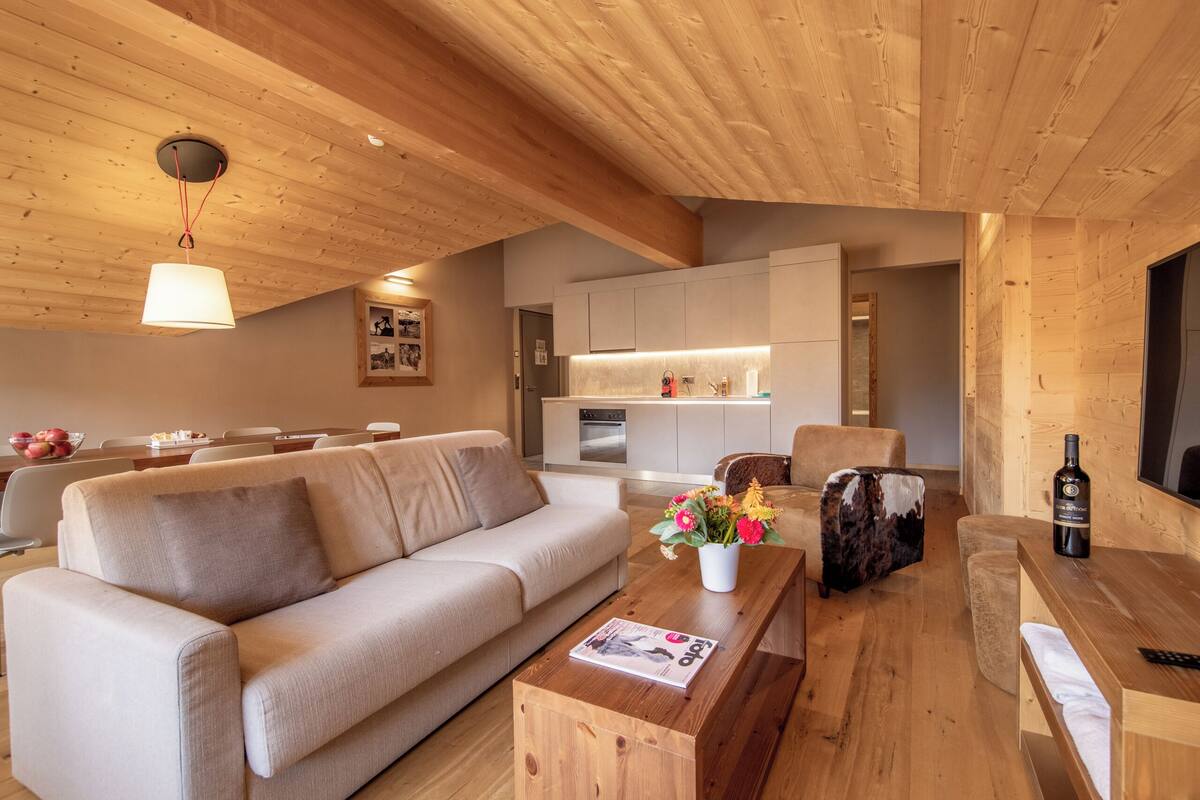 A modern living room with a sofa, coffee table, and a dining area.