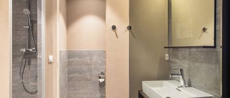 A modern bathroom with a shower, a sink, and a mirror.