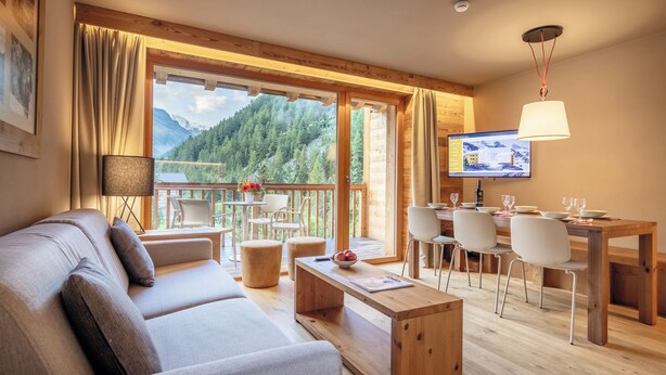 A modern living room with a sofa, coffee table, and dining area with chairs and a TV.