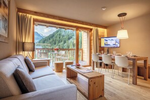 Un salon moderne comprenant un canapé, une table basse et un coin repas avec des chaises et un téléviseur.