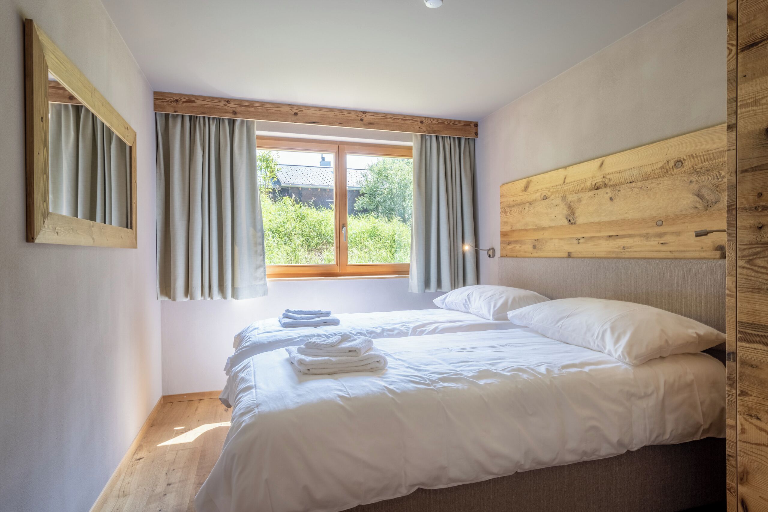 Un dormitorio con cama, cortinas, cabecero de madera y ventana.