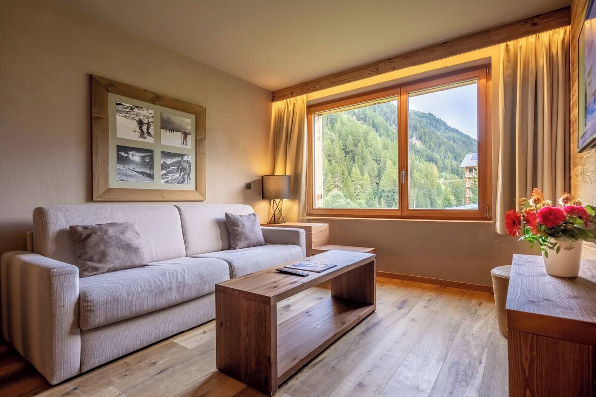 A living room with a sofa, coffee table, and a large window with curtains.