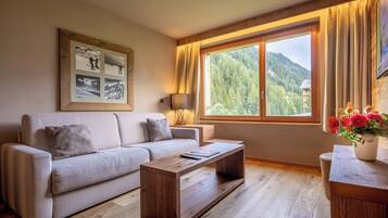 A living room with a sofa, coffee table, and a large window with curtains.