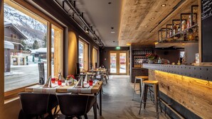 A restaurant with a bar area, large windows, and a view of the outside.