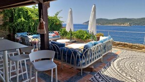 Una terraza con mobiliario exterior, vista al mar y un tapete estampado.