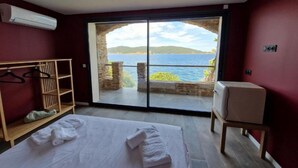 Un dormitorio con un amplio ventanal corredera que da a un balcón con vistas al mar.