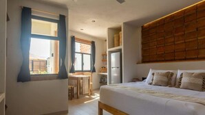 A bedroom with a large bed, a wooden headboard, a desk with a chair, and a window with curtains. - Casa Aymara 601: Beach, Starlink & Privacy (Brisas de Zicatela)
