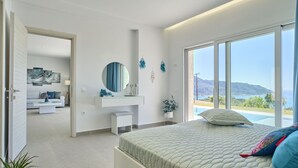 Un dormitorio moderno con una cama grande, un tocador y vista al mar.
