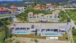 Un barrio residencial con varias casas, una piscina y vistas a las montañas.