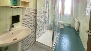 Un baño con ducha de vidrio, lavamanos e inodoro.