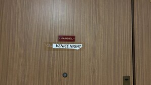 Una puerta de madera con una placa que dice "HANDEL" y un cartel que indica "NOCHE VENECIA".
