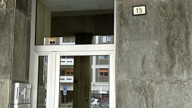 Entrada de un edificio con puerta de vidrio, escalera de metal y el número 13.