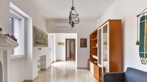 A hallway with a marble floor, a dark grey sofa, a wooden bookshelf, and a painting on the wall.