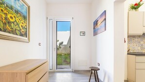 A hallway with a wooden bench, a glass door leading outside, and a small stool.