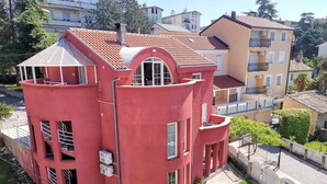 A red, multi-story building with balconies, large windows, and a tiled roof. - Nice apartment near beach and city ​​centre (Crikvenica)