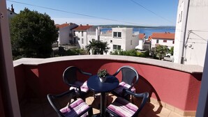 A balcony with a table and chairs, overlooking a coastal town with buildings and a clear sky. - Nice apartment near beach and city ​​centre (Crikvenica)