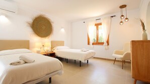 A hotel room with two beds, a wooden chair, a desk, and a window with curtains.
