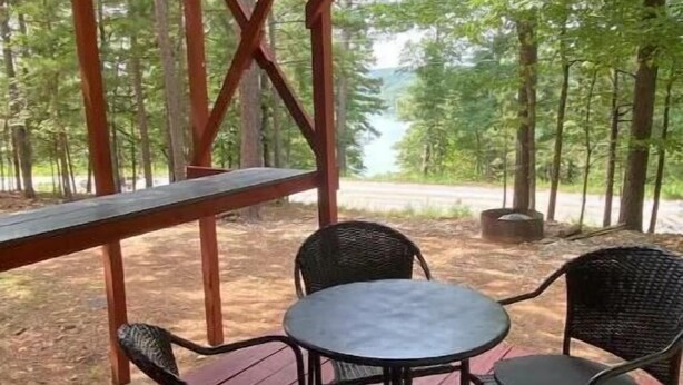 An outdoor patio with a wooden deck, metal chairs, and a round table. - Beaver Dome Geodesic Lake Home 3br 2bath (Rogers)
