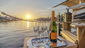A bottle of Veuve Clicquot champagne and four glasses on a tray by a waterfront.