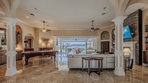 A spacious living room with a pool table, a comfortable seating area, and a view of the outdoors.