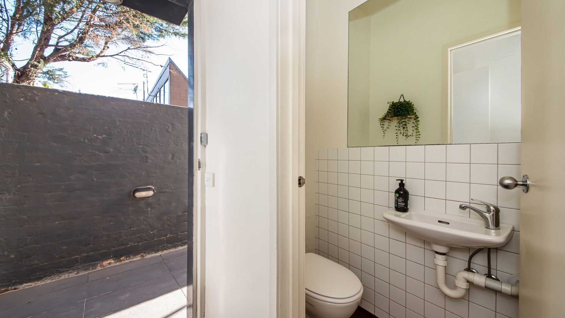 Een badkamer met toilet, wastafel en spiegel.
