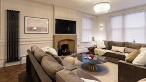 A living room with a fireplace, two sofas, a coffee table, and a chandelier.