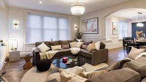 A spacious living room with a large sectional sofa, a round coffee table, and a chandelier.