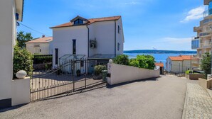 Ein zweistöckiges Gebäude mit rotem Ziegeldach, einem überdachten Eingang mit Glasdach und Blick aufs Meer.