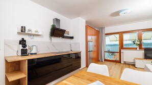 Eine moderne Küche mit einer Holzarbeitsplatte, integrierten Geräten und Meerblick durch große Fenster.