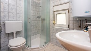 A bathroom with a glass-enclosed shower, a toilet, and a sink. - Modern studio flat 500 metres to the beach (Dramalj)