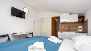 A hotel room with a bed, a desk, a TV, a kitchenette, and a bathroom. - Modern studio flat 500 metres to the beach (Dramalj)