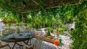 An outdoor patio with a round table and chairs, surrounded by lush greenery and potted plants. - Modern studio flat 500 metres to the beach (Dramalj)