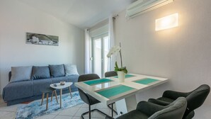 A modern living room with a sofa, a dining table with chairs, a small side table, and a potted plant. - Great sea view only 500 metres to the beach (Dramalj)