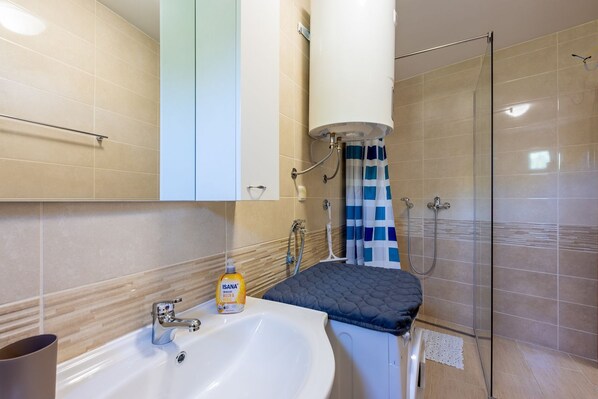 A bathroom with a sink, toilet, shower, and a towel rack.