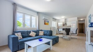 A modern living room with a sofa, a coffee table, and a dining area with chairs and a table.