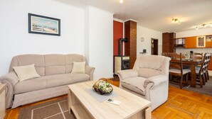 Una sala de estar con sofá, sillón, mesa de centro y un comedor con sillas y mesa.