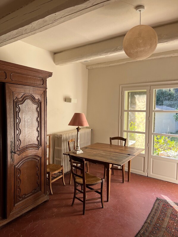 A dining area with a wooden table, chairs, a lamp, and a radiator.