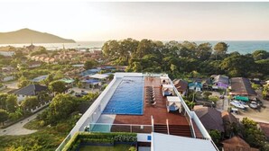 Una piscina en la azotea con vistas al mar y edificios circundantes.