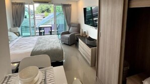 Una habitación de hotel con cama, escritorio con comedor, televisor y armario.
