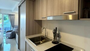 Una cocina moderna con armarios de madera, un lavamanos de acero inoxidable y una encimera negra.