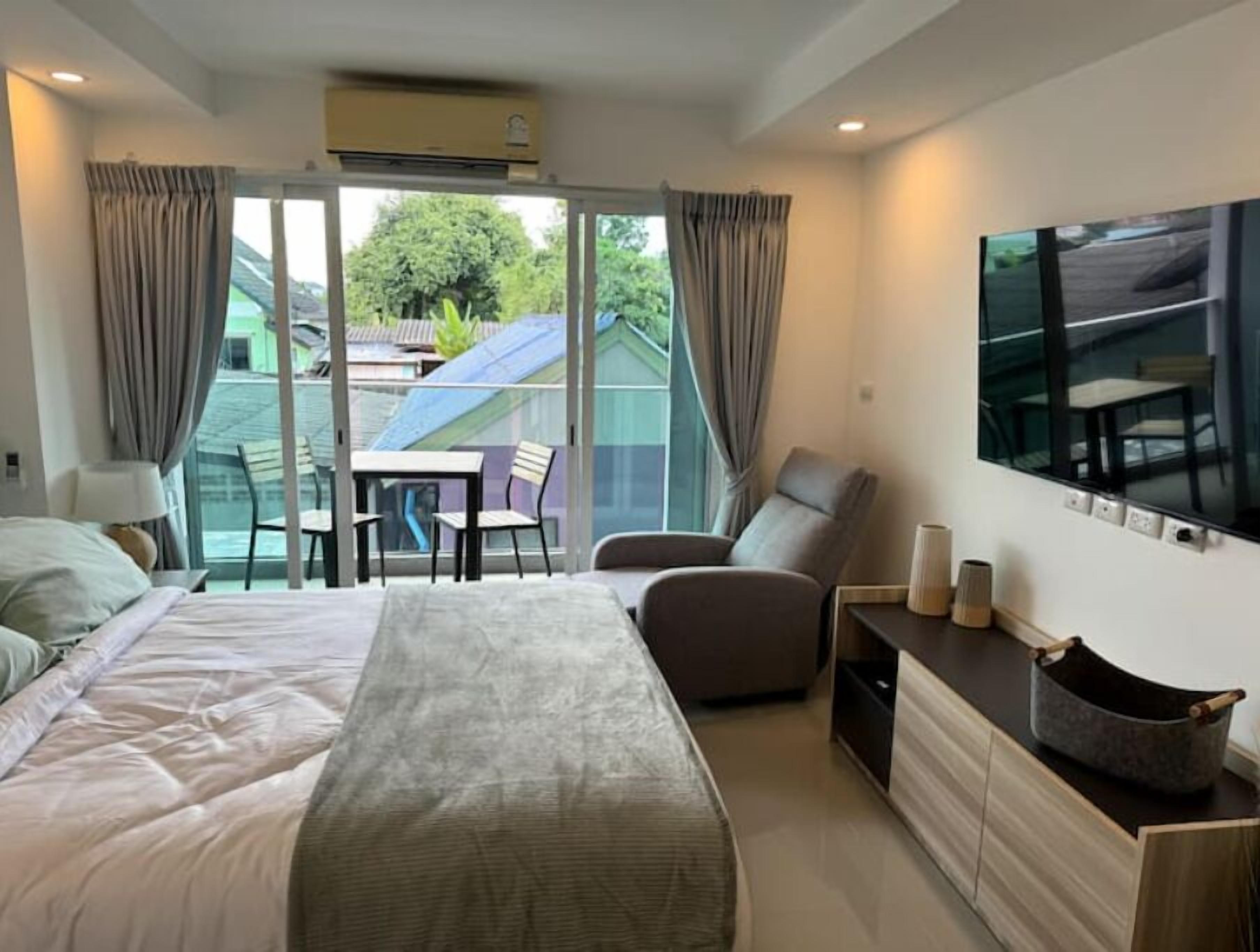 A bedroom with a bed, a chair, a table, and a TV.