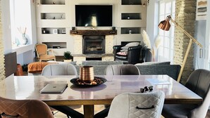 Un salon moderne avec une cheminée, une table à manger avec des chaises et un téléviseur fixé au mur.