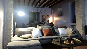 Un salon chaleureux avec un canapé d’angle, une table basse et des piliers en pierre.