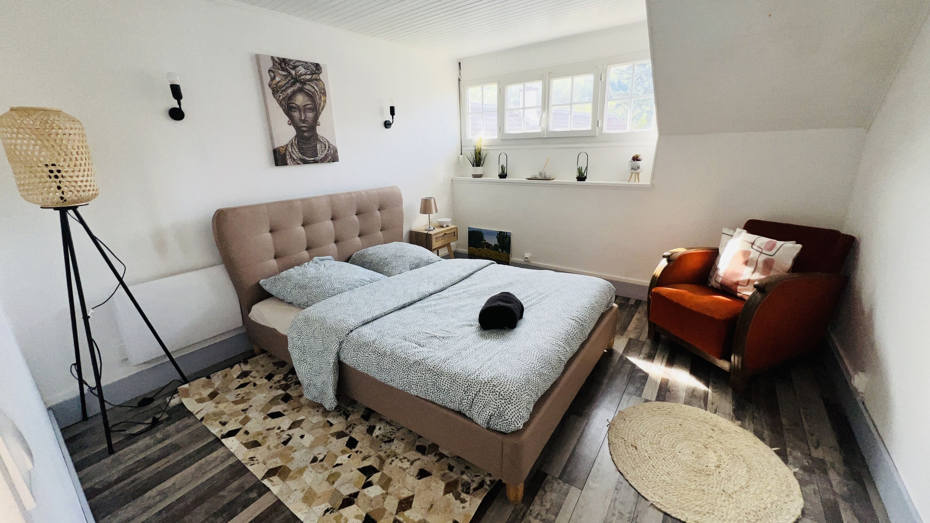 Een slaapkamer met een groot bed, een stoel, een vloerlamp en een raam met uitzicht.