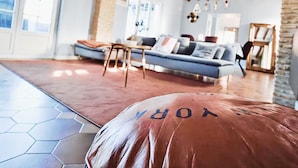 Un salon spacieux avec un grand canapé, une table basse et un pilier en pierre.