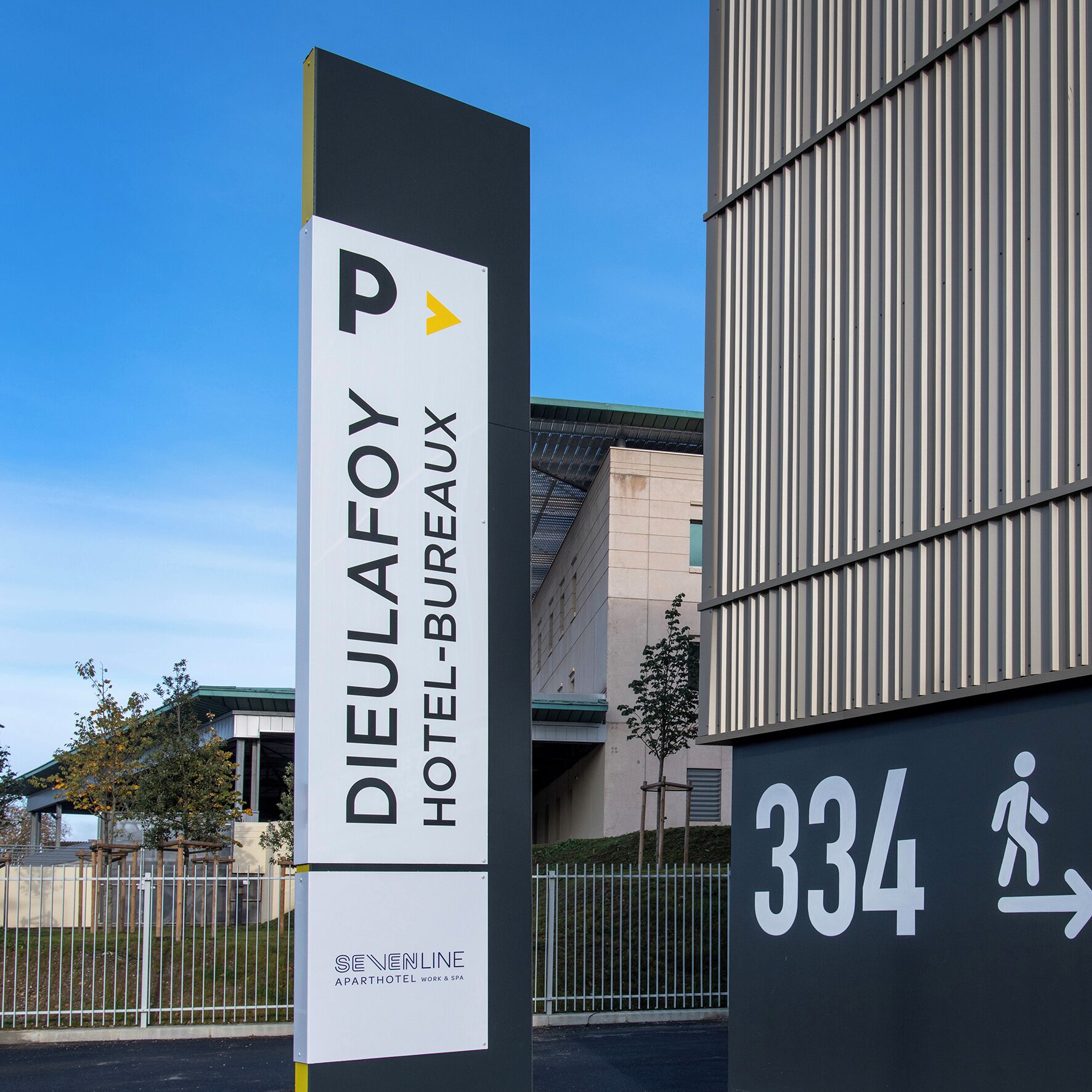 Señal del Hotel Dieulafoy-Bureau con un símbolo de estacionamiento, indicando un área de estacionamiento cerca.