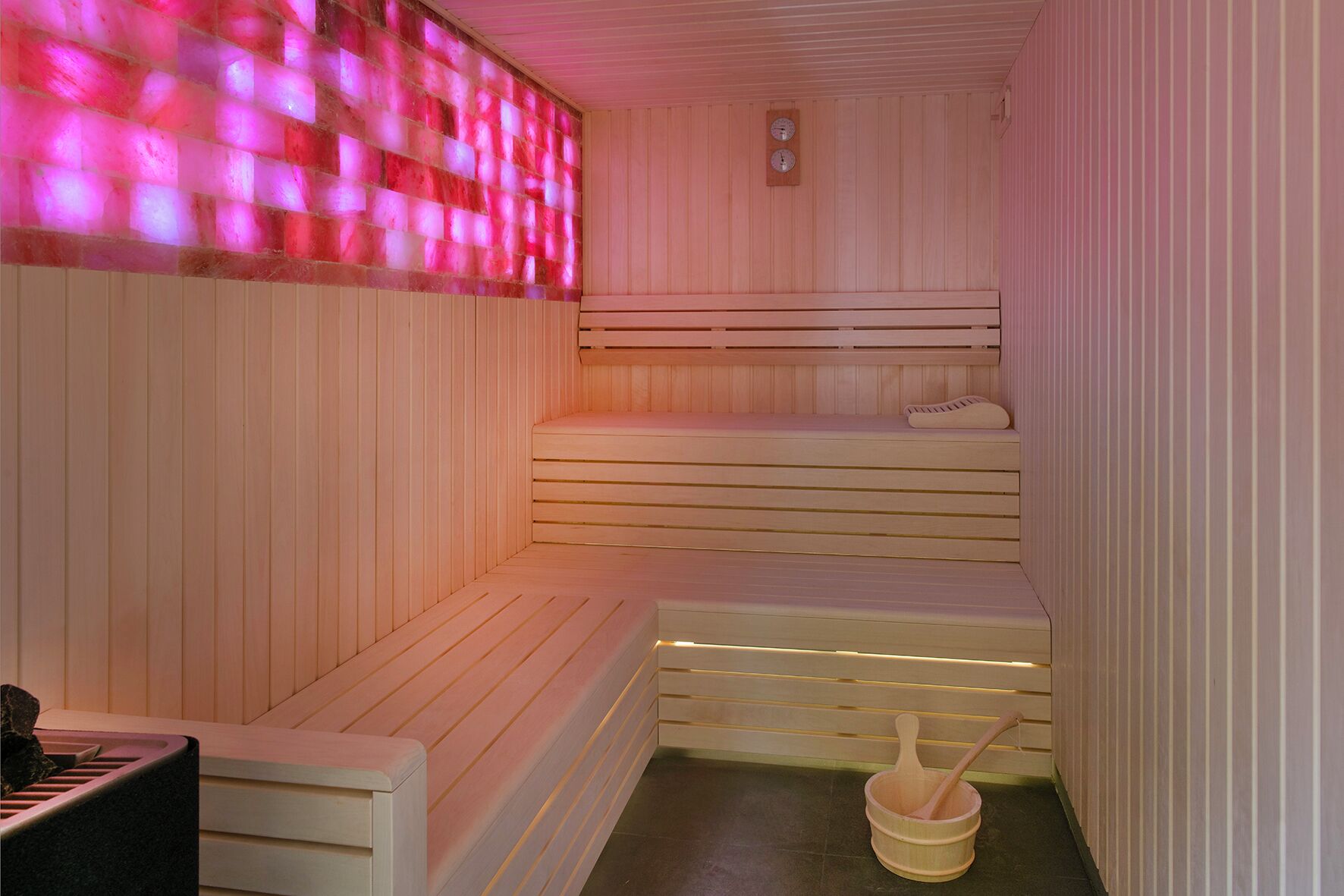 A sauna with wooden benches and a wooden bucket with a wooden spoon.