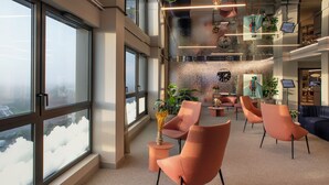 A modern office space with large windows, a variety of seating arrangements, and indoor plants. - Sevenline Aparthotel Purpan Toulouse (Toulouse)