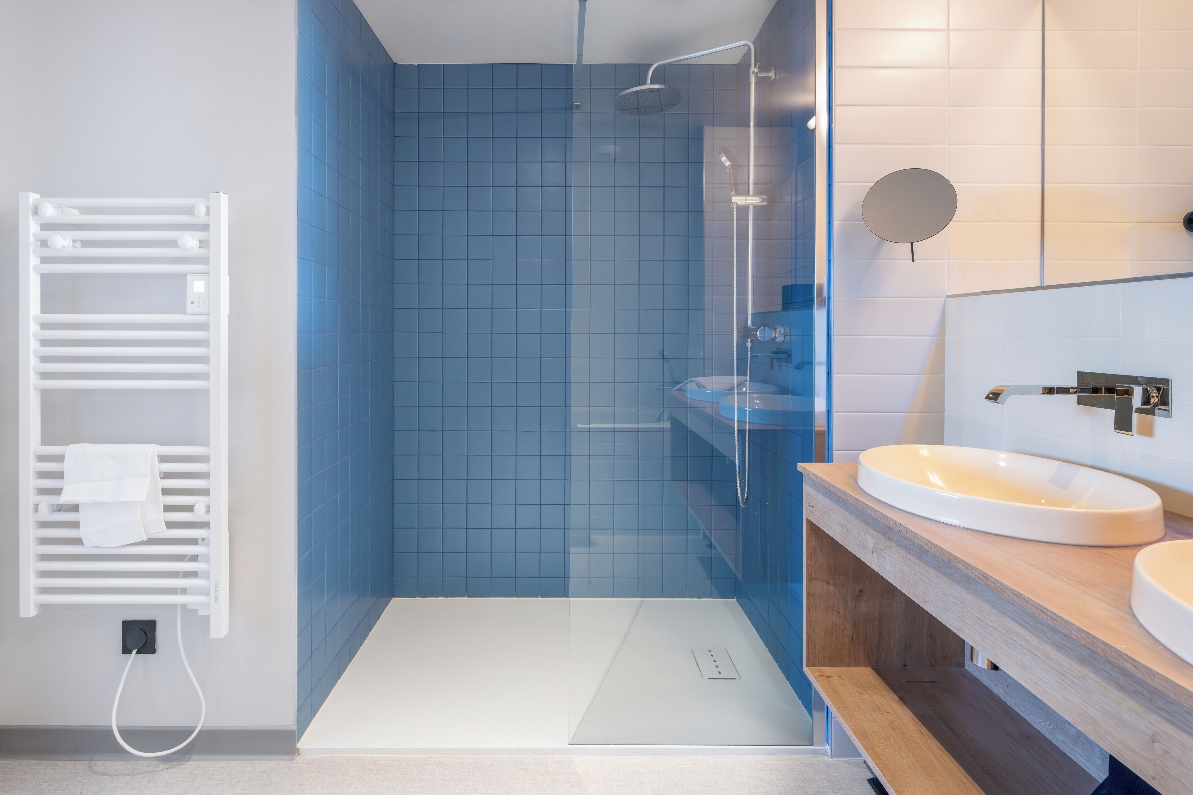 Ein modernes Badezimmer mit einer Duschkabine, einem weißen Handtuchhalter und einem Holzbadezimmermöbel mit Waschbecken.